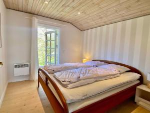 Fantastic Spa-house Surrounded By Nature في Udsholt Sand: سرير في غرفة ذات سقف خشبي