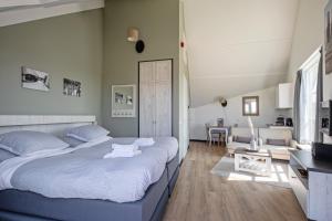 a bedroom with a large bed and a living room at Strandplevier Suites in De Koog