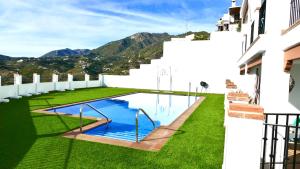 uma piscina ao lado de um edifício com relva verde em Casita Frigiliana - stunning new apartment with views with private parking space em Frigiliana