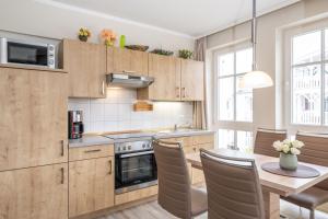 uma cozinha com armários de madeira e uma mesa com cadeiras em Fewo 405, Seepark Sellin em Ostseebad Sellin