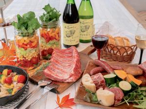 a table topped with meats and vegetables and glasses of wine at Nagano GLAMPINGBASE enCamp in Shiojiri