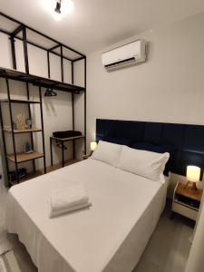 a bedroom with a large white bed with two towels on it at Loft 61 - No coração de Curvelo in Curvelo