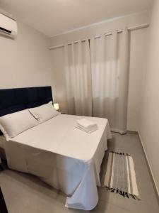 a bedroom with a white bed and a window at Loft 61 - No coração de Curvelo in Curvelo