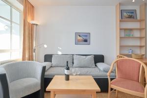 ein Wohnzimmer mit einem Sofa und 2 Stühlen in der Unterkunft Fewo 647, Seepark Sellin in Ostseebad Sellin