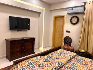 1 dormitorio con 1 cama, TV y silla en Luxuriant 3 Bed Apartment Defence Residency DHA Phase 2 Islamabad The Realtors Inn en Islamabad