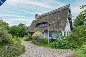 a white house with a thatched roof and a brick driveway at Ferienanlage am Gothensee 25 Kreativhaus am See in Gothen