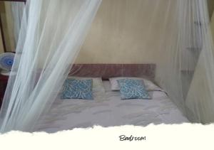 a bed with white curtains and blue pillows on it at HEINER HOMESTAY in Bunaken