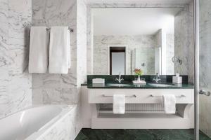 ein Badezimmer mit zwei Waschbecken, einer Badewanne und einem Spiegel in der Unterkunft Anantara New York Palace Budapest - A Leading Hotel of the World in Budapest