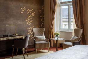 a bedroom with a bed and two chairs and a desk at Anantara New York Palace Budapest - A Leading Hotel of the World in Budapest