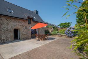 - une terrasse avec 2 chaises et un parasol orange dans l'établissement Charmante maison toute équipée, proche de Lorient, à Cléguer