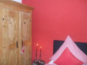 una camera da letto con una parete rossa e un letto con due candele di Ferienwohnung Alpensonne a Oberstdorf