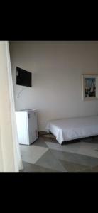 - une chambre avec un lit et une télévision murale dans l'établissement Casa em Frente ao Mar, à Prado