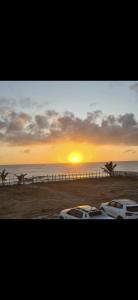 - deux voitures blanches garées sur la plage au coucher du soleil dans l'établissement Casa em Frente ao Mar, à Prado