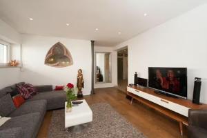 uma sala de estar com um sofá e uma televisão de ecrã plano em Apartment City Uniklinik em Friburgo em Brisgóvia