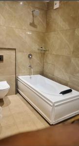 a bathroom with a bath tub and a toilet at HOTEL PEARL WOOD (A unit of olive hospitality group) in Zirakpur