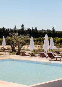 uma piscina com espreguiçadeiras e guarda-sóis em Casas da Quinta de Cima em Vila Nova de Cacela