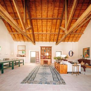 una gran sala de estar con techos de madera y una alfombra. en Casas da Quinta de Cima en Vila Nova de Cacela