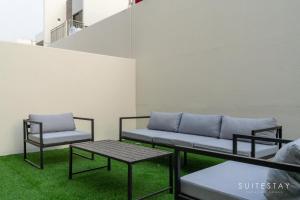 Boho Inspired Large Luxury Villa في دبي: كرسيين وأريكة في غرفة بها عشب