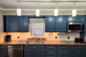 eine Küche mit blauen Schränken, einer Spüle und einer Mikrowelle in der Unterkunft Large Cozy House Near NexusPark Air Hockey in Columbus