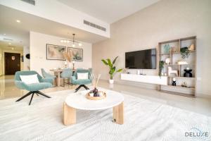 a living room with a tv and a table and chairs at Beautiful 3BR Villa with Assistant Room Al Dana Island, Fujairah by Deluxe Holiday Homes in Fujairah