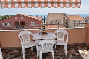 una mesa y sillas en un balcón con vistas en Apartments Bella Sky V en Novalja