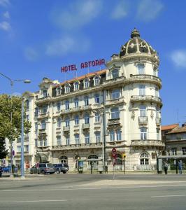 Un grand bâtiment blanc avec un panneau en haut dans l'établissement Hotel Astoria, à Coimbra