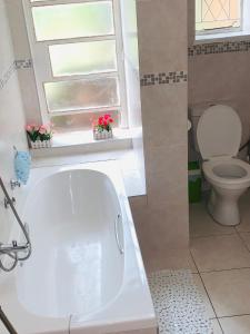 a bathroom with a white tub and a toilet at Naisiae - Lovely 1-bedroom vacation home with pool in Johannesburg