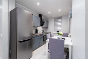 uma cozinha com um frigorífico de aço inoxidável e uma mesa em Stylish Apartment For up to 4 Guests With WiFi, Free Parking em Vilkaviškis