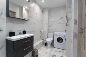 a white bathroom with a washing machine and a washer at Stylish Apartment For up to 4 Guests With WiFi, Free Parking in Vilkaviškis