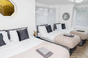 three beds in a room with white walls and windows at Elegant House with Garden&Parking in Southampton