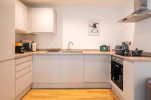 a kitchen with white cabinets and a sink at Leeds City Centre Duplex 3 Bedroom 3 Bath stunning Flat with Rooftop Terrace and Parking in Leeds