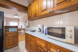 a kitchen with wooden cabinets and a microwave at Sofihome Ampelokipi Station in Athens