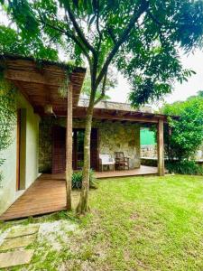 a house with a wooden deck and a tree at Camburi Beach House - Casa térrea a 50 m da praia in São Sebastião