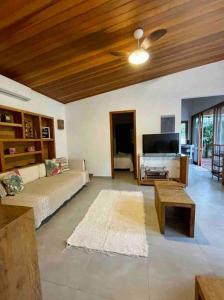 a living room with a couch and a flat screen tv at Camburi Beach House - Casa térrea a 50 m da praia in São Sebastião