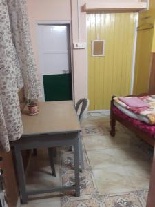 een kamer met een tafel, een bed en een deur bij Hotel New Smriya Homestay Inn Darjeeling in Darjeeling