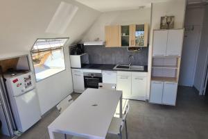 a kitchen with white cabinets and a table and a sink at Tipi des dunes in Surtainville