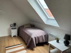 a bedroom with a bed in a attic with a window at Oustrupgård in Egtved