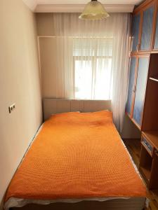 uma cama laranja num quarto com uma janela em Konfor ve huzurunuz için her şey var klimasız oda em Antalya
