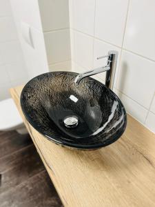 a black bathroom sink sitting on a wooden counter at Sušilova 14 apartments II in Přerov