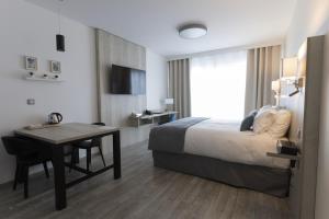 um quarto de hotel com uma cama, uma secretária e uma mesa em Les Terrasses du Port em Saint-Pierre