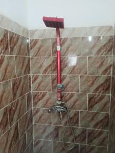 prysznic z czerwonym wężem w wyłożonej kafelkami łazience w obiekcie Venus house15 w mieście Raoued