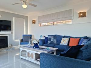a living room with a blue couch and a table at Summer Tides in Gordonʼs Bay