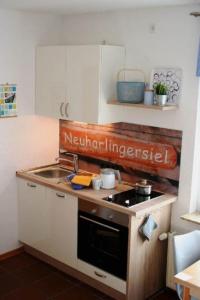eine kleine Küche mit Herd und Spüle in der Unterkunft Haus Rika 2 in Neuharlingersiel