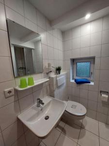 ein Badezimmer mit einem Waschbecken, einem WC und einem Spiegel in der Unterkunft Haus Rika 2 in Neuharlingersiel