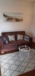 ein braunes Sofa im Wohnzimmer mit einem Tisch in der Unterkunft Haus Rika 2 in Neuharlingersiel