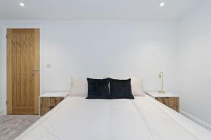 Una cama blanca con dos almohadas negras. en Stylish Beach Front Retreat en Kent