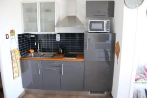 eine kleine Küche mit einer Spüle und einer Mikrowelle in der Unterkunft Studio 34, Héliopolis E au village naturiste in Cap d'Agde