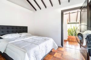a white bedroom with a bed and a window at 3 Story Penthouse with 2 parking spaces in Laureles in Medellín