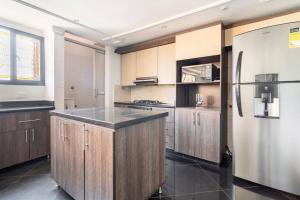 a kitchen with wooden cabinets and a stainless steel refrigerator at 3 Story Penthouse with 2 parking spaces in Laureles in Medellín