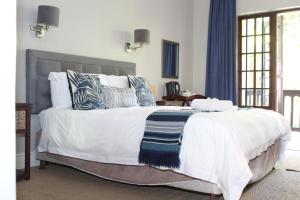 a bedroom with a large white bed with pillows at Sir Roys Guest House in Port Elizabeth